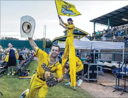  ?? KATELYN MYRICK/FOR THE AJC ?? The team members of the Savannah Bananas — complete with a stilt-walking, flag-waving Banana — make their entrance at the 2024 Banana Ball World Tour draft on Thursday in Savannah. The wacky, circus-like approach to baseball has generated a vast audience of followers on social media and in ballparks around the country.