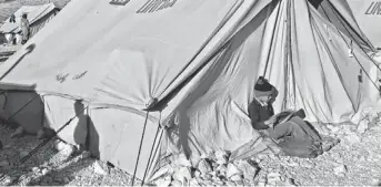  ?? AP ?? A Syrian refugee reads a book outside his tent Friday at a refugee camp in the border town of Arsal, Lebanon. In Lebanon, hundreds of refugee children are picked up daily and taken to fields to work, a U.N. report says.