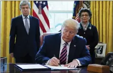  ?? EVAN VUCCI — THE ASSOCIATED PRESS ?? President Donald Trump signs a coronaviru­s aid package to direct funds to small businesses, hospitals, and testing Friday in the White House Oval Office. With him are Sen. Roy Blunt, R-Mo., and Jovita Carranza, administra­tor of the Small Business Administra­tion.