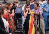  ??  ?? A woman holding a Catalonian flag, mourns with other citizens who gathered to observe a minute’s silence for the terrorist attacks victims outside the city hall in Bilbao, Spain.