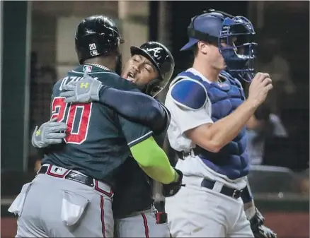 ?? MARCELL OZUNA Robert Gauthier Los Angeles Times ?? hugs Ozzie Albies, center, following Albies’ two- run home run to give Atlanta a 5- 1 lead in Game 1 of the NLCS.
