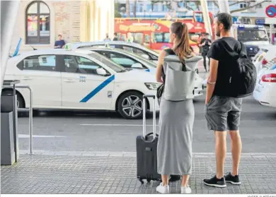  ?? JAVIER ALBIÑANA ?? Dos turistas esperan la llegada de un transporte público en Málaga.