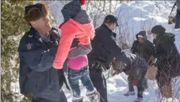  ?? PAUL CHIASSON, THE CANADIAN PRESS ?? Family members from Somalia are helped into Canada by RCMP officers along the U.S.-Canada border near Hemmingfor­d, Que.