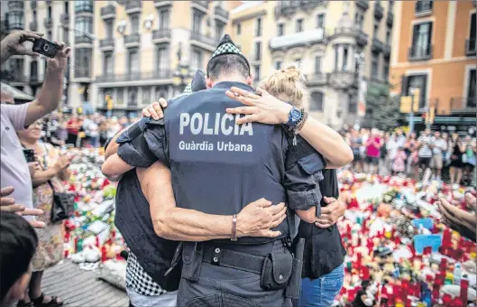  ?? SANTI PALACIOS/THE ASSOCIATED PRESS ?? At a memorial site Aug. 21, a policeman hugs a boy and his family who he helped during the terrorist attack on Las Ramblas in Barcelona, Spain.