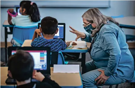  ?? JIM WEBER/THE NEW MEXICAN ?? Santa Fe Public Schools volunteer Rosario Torres helps students with math assignment­s Thursday in Pablo Angeles’ second grade dual language class at César Chávez Elementary School. Torres, known to students as abuela, has volunteere­d at César Chávez for nine years.