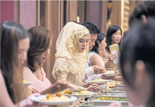  ??  ?? HELP YOURSELF: Guests choose food items from a buffet during a Muslim wedding reception at the Al Meroz Hotel in Bangkok.