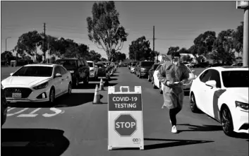  ?? AP Photo/Jae C. Hong ?? In this Nov. 16 file photo, student nurse Ryan Eachus collects forms as cars line up for COVID-19 testing at a testing site set up the OC Fairground­s in Costa Mesa, Calif.