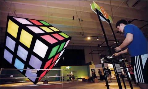  ?? (File Photo/AP/Ted S. Warren) ?? Kevin Hays of Renton, Wash., uses a computer console June 10, 2012, to solve the Groovik’s Cube, an electronic 15-foot Rubik’s Cube puzzle, at the Pacific Science Center in Seattle.