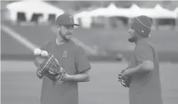  ?? DARRONCUMM­INGS| AP ?? Angels’ Matt Andriese, left, and Jaime Barria talk after throwing during spring training last season. The Angels pitchers and catcher start workouts on Wednesday.