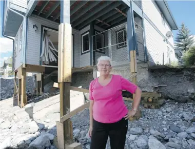  ?? Leah Hennel/calgary Herald ?? Marion Kutzer stands outside what is left of her home in Canmore after it and other homes along Cougar Creek were destroyed in the floods. She and her husband, Paul, have received expert opinion that says the house is too dangerous to even do an assessment on, but the province denied their request for disaster assistance.