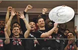  ?? (AFP) ?? Bayer Leverkusen’s coach Xabi Alonso celebrates with a mock-up of the Bundesliga trophy with his players after the match against Werder Bremen in Leverkusen, Germany, yesterday.