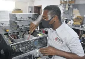  ??  ?? Algarreou Mcleod, an MPCT technician, conducts repairs on an IT system.