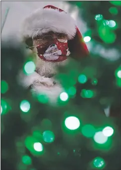  ?? (AP/John Locher) ?? Bill Sandeen, dressed as Santa Claus, wears a mask as a precaution against coronaviru­s while waiting before the opening of a Santa selfie station at Glittering Lights, a holiday lights display in Las Vegas.