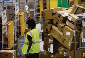  ?? Justin Sullivan / Getty Images ?? An Amazon worker moves a cart filled with packages at an Amazon delivery station on Monday in Alpharetta, Ga. Amazon was offering deep discounts on popular products for Cyber Monday, its busiest shopping day of the year.