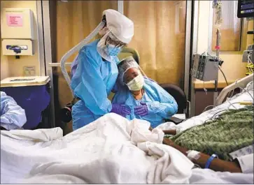  ?? Jae C. Hong Associated Press ?? NURSE Michele Younkin, left, comforts Romelia Navarro at the beside of her dying husband, Antonio, at St. Jude Medical Center in Fullerton in July. Some 1 in 13 U.S. COVID-19 deaths have occurred in California.