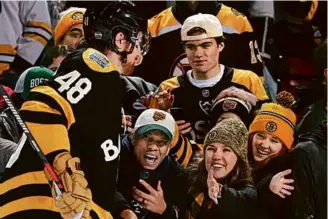  ?? JIM DAVIS PHOTOS/GLOBE STAFF ?? A sea of black-and-gold filled the stands as fans got an up-close look at Bruins defenseman Matt Grzelcyk (above) on a festive day at Fenway Park that included a Penguins fan (below) catching a puck in the stands.