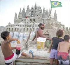  ?? MAURO PIMENTEL/AFP ?? Marcio Mizael Matolias speaks with children who are interested in his sand castle, at Barra da Tijuca beach in Rio de Janeiro.