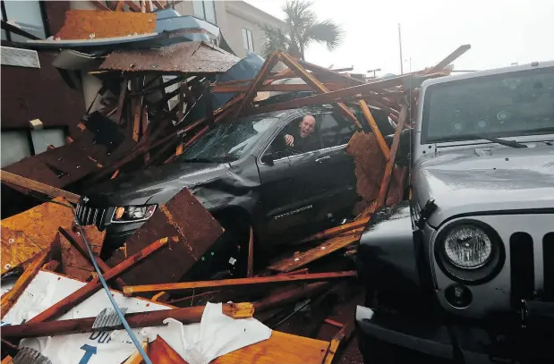  ?? GERALD HERBERT / THE ASSOCIATED PRESS ?? A storm chaser climbs into his car during the eye of Hurricane Michael to retrieve equipment after a hotel canopy collapsed in Panama City Beach, Fla.