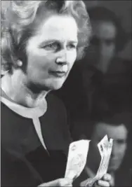  ?? THE ASSOCIATED PRESS ?? Conservati­ve Party leader Margaret Thatcher holds up five one-pound notes during a speech April 30, 1976, in Finchley, North London. “Every time you spend five pounds,” she said, “the Government owes one to creditors abroad.” The pound has endured a...