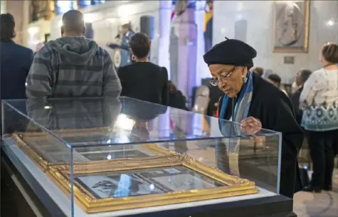  ?? Stephanie Strasburg/Post-Gazette ?? Cassie Brandon, 75, of Downtown, looks at a display during the opening reception for the exhibit, “Enslavemen­t &amp; Freedom: Early African-American Life in Pittsburgh,” on Feb. 5 at the City-County Building in Downtown. The exhibit contains a small fraction of John L. Ford's collection of artifacts from black history from Africa and Pittsburgh and is on display until Feb. 28.