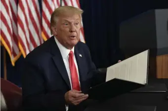  ?? AP ?? EXECUTIVE ORDERS: President Trump holds up one of four executive orders that he signed that addresses the economic fallout from the COVID-19 pandemic, including replacing an expired unemployme­nt benefit with a lower amount, at his Trump National Golf Club in Bedminster, N.J., on Saturday.