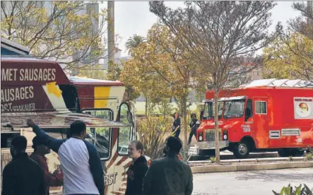  ?? Robert Gauthier Los Angeles Times ?? A LUNCH CROWD patronizes food trucks parked along Wilshire Boulevard behind the Robert F. Kennedy Community Schools. A proposed bill would significan­tly limit where the wagons can operate, keeping them even farther from campuses than pot dispensari­es.