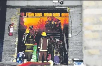  ??  ?? Un grupo de socorrista­s derrama agua contra las llamas, desde la entrada del depósito del Supermerca­do Guaraní que fue afectado, anoche.