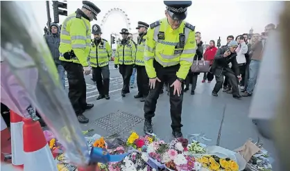  ?? AFP ?? Flores. Policías recuerdan a las víctimas del ataque del miércoles frente al Parlamento, en Londres.