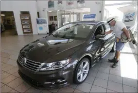  ?? DAMIAN DOVARGANES — THE ASSOCIATED PRESS ?? A customer checks the interior of a 2015 Volkswagen CC sports car for sale at the New Century Volkswagen dealership in Glendale, Calif.