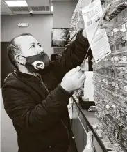  ??  ?? Uddin grabs scratch-off tickets for customers at Lucky Rudy’s, a popular lottery retailer in Rosenberg.