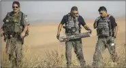  ?? AP/TSAFRIR ABAYOV ?? Israeli police bomb disposal officers remove a rocket Wednesday that was fired from the Gaza Strip into farmland near the Gaza border.