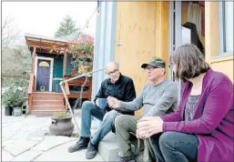  ?? Karen Ducey For The Times ?? DAN TENENBAUM, left, and Kim Sherman chat with Robert Desjarlais, a former homeless man who lives in a cottage in the Seattle couple’s backyard.