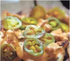  ??  ?? The pimento cheese fries are melted pimento cheese and with pickled jalapenos