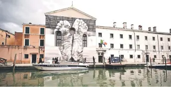  ?? — AFP photo ?? A mural by artist Maurizio Cattelan is seen outside Giudecca Women’s Prison hosting the Holy See pavilion during the pre-opening of the 60th Venice Biennale art show in Venice.