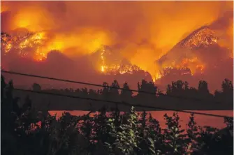  ??  ?? A wildfire burns in the Columbia River Gorge above Cascade Locks, Oregon, in September 2017. The teen who started the fire has been ordered to pay restitutio­n for at least the next decade.