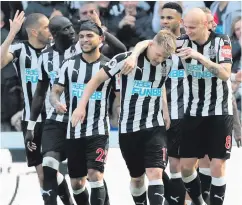 ??  ?? Staying up: Matt Ritchie is mobbed after hitting Newcastle’s winner