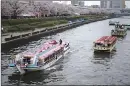  ??  ?? A tourist boat passes by other boats staying near the cherry blossoms in full bloom along the Sumida River in Tokyo.