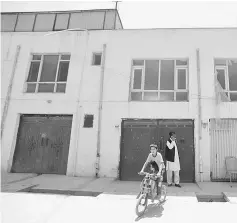  ?? — Reuters photo ?? An Afghan boy rides his bicycle in front of the house where the German aid worker and an Afghan guard were killed.