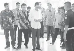  ??  ?? Widodo (centre) looks at a book as he arrives for work at city hall in Jakarta. — Reuters photo