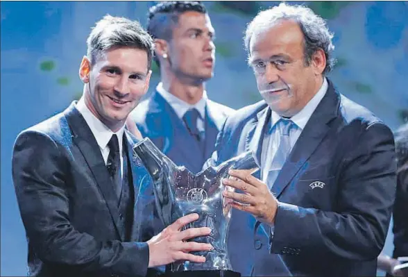  ?? GUILLAUME HORCAJUELO / EFE ?? De diez a diez. Leo Messi recoge el trofeo de manos de Michel Platini, presidente de la UEFA, mientras Cristiano Ronaldo mira hacia otro lado