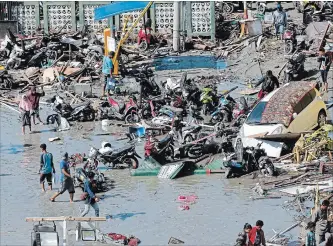  ?? TATAN SYUFLANA THE ASSOCIATED PRESS ?? People survey damage at a shopping mall Sunday after an earthquake and a tsunami in Palu. President Joko Widodo says authoritie­s are deploying more heavy machinery so workers can recover more victims Monday.