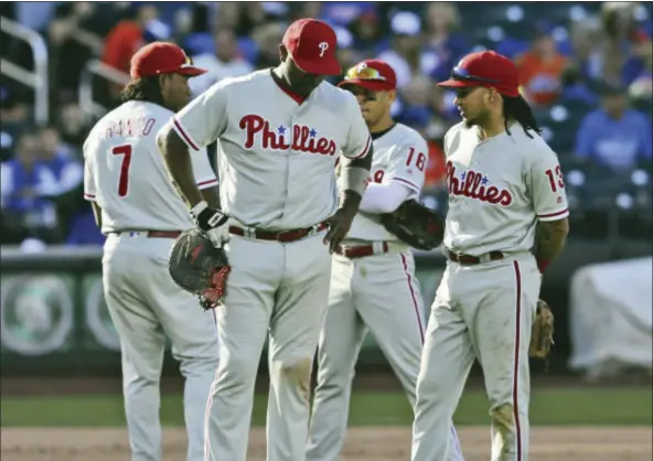  ?? SETH WENIG — THE ASSOCIATED PRESS ?? Philadelph­ia Phillies’ Ryan Howard, second from left, and other teammates wait during a pitching change during the eighth inning of the baseball game against the New York Mets at Citi Field, Sunday in New York.
