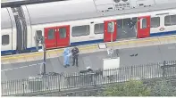  ??  ?? Investigat­ing officers stand on the station’s platform