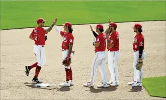  ?? DAVID JABLONSKI / STAFF ?? The Reds celebrate after a victory against the Pirates on Wednesday at Great American Ball Park. The Reds won 11-4, bringing their season run total to 57 in six games.