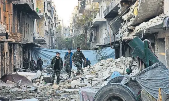  ?? GEORGE OURFALIAN / AFP ?? Miembros del ejército sirio de El Asad, ayer, en tareas de reconocimi­ento caminando entre los escombros en un barrio de Alepo