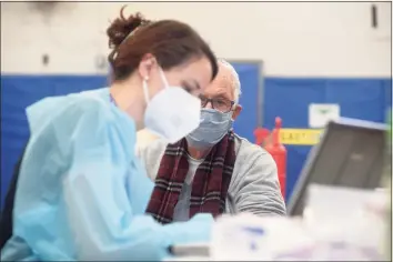  ?? H John Voorhees III / Hearst Connecticu­t Media ?? Registered nurse Bridget Bethray, of RVNAhealth, takes informatio­n before administer­ing a COVID-19 vaccine to Sherwin Gorenstein, of Ridgefield, at the RVNA clinic in the Yanity Gym in Ridgefield on Feb. 4.