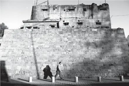  ?? Associated Press ?? A man crosses the Pathos Gate of Venetian wall that surrounds the old city on Tuesday in the divided capital of Nicosia, Cyprus. At talks to end Cyprus’ 43-year ethnic divide at the Swiss ski resort of Crans-Montana, Turkish Foreign Minister Mevlut...