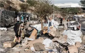  ?? AFP ?? Varios miembros de la comunidad local limpian los escombros luego de los continuos saqueos y destrucció­n en Durban.