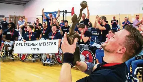  ??  ?? Kapitän Raimund Beginskis hält die Meister-trophäe stolz in der Hand. Seine Mannschaft­skollegen feiern im Hintergrun­d. Fotos (): Sascha Fromm