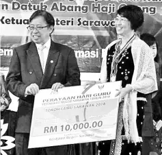  ??  ?? Abang Johari (left) presenting a mock cheque for RM10,000 to Chong who was named as Tokoh Guru Sarawak 2018.